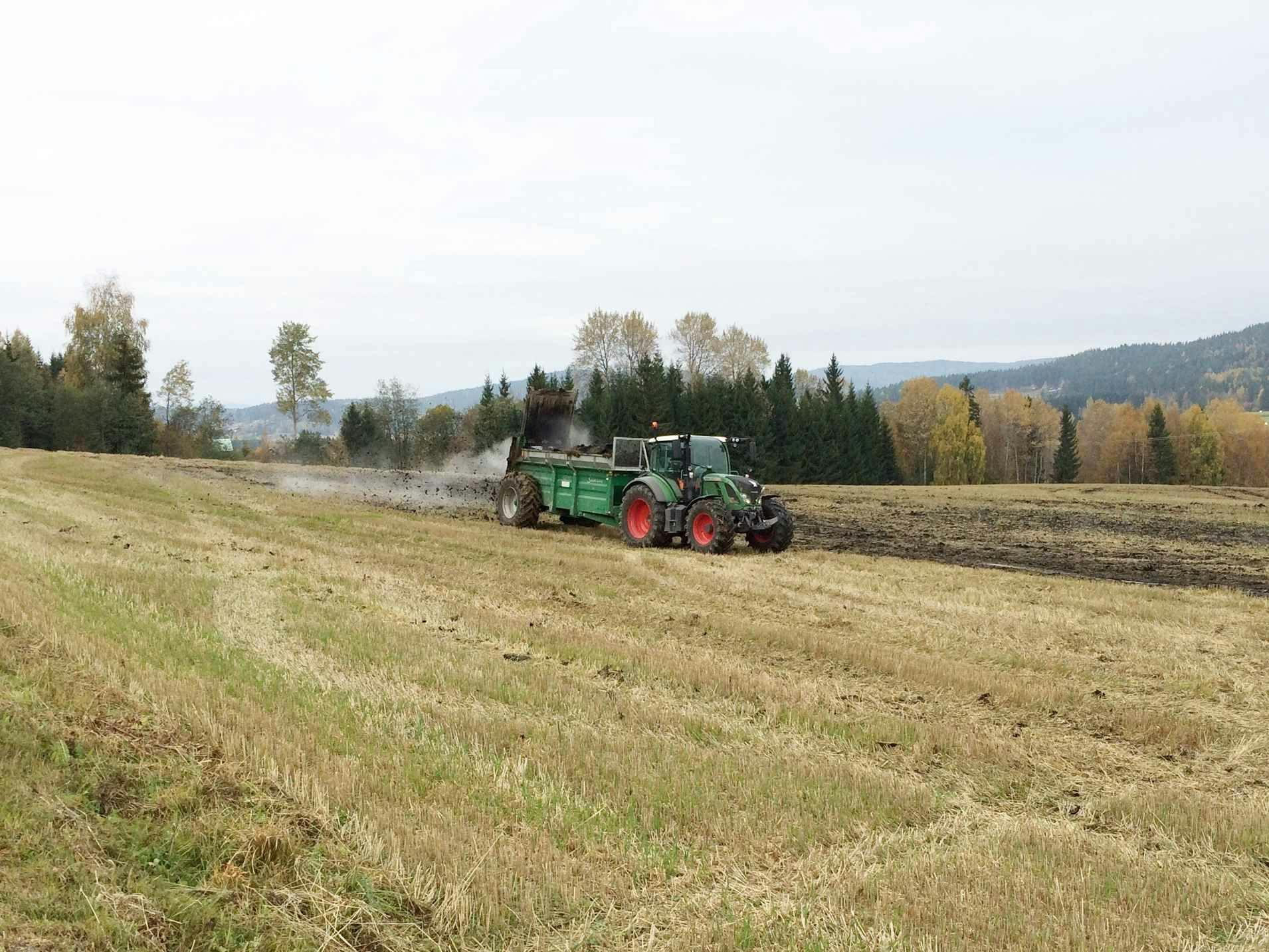 Spredning av biorest på et jordet ved bruk av traktor. Foto. 